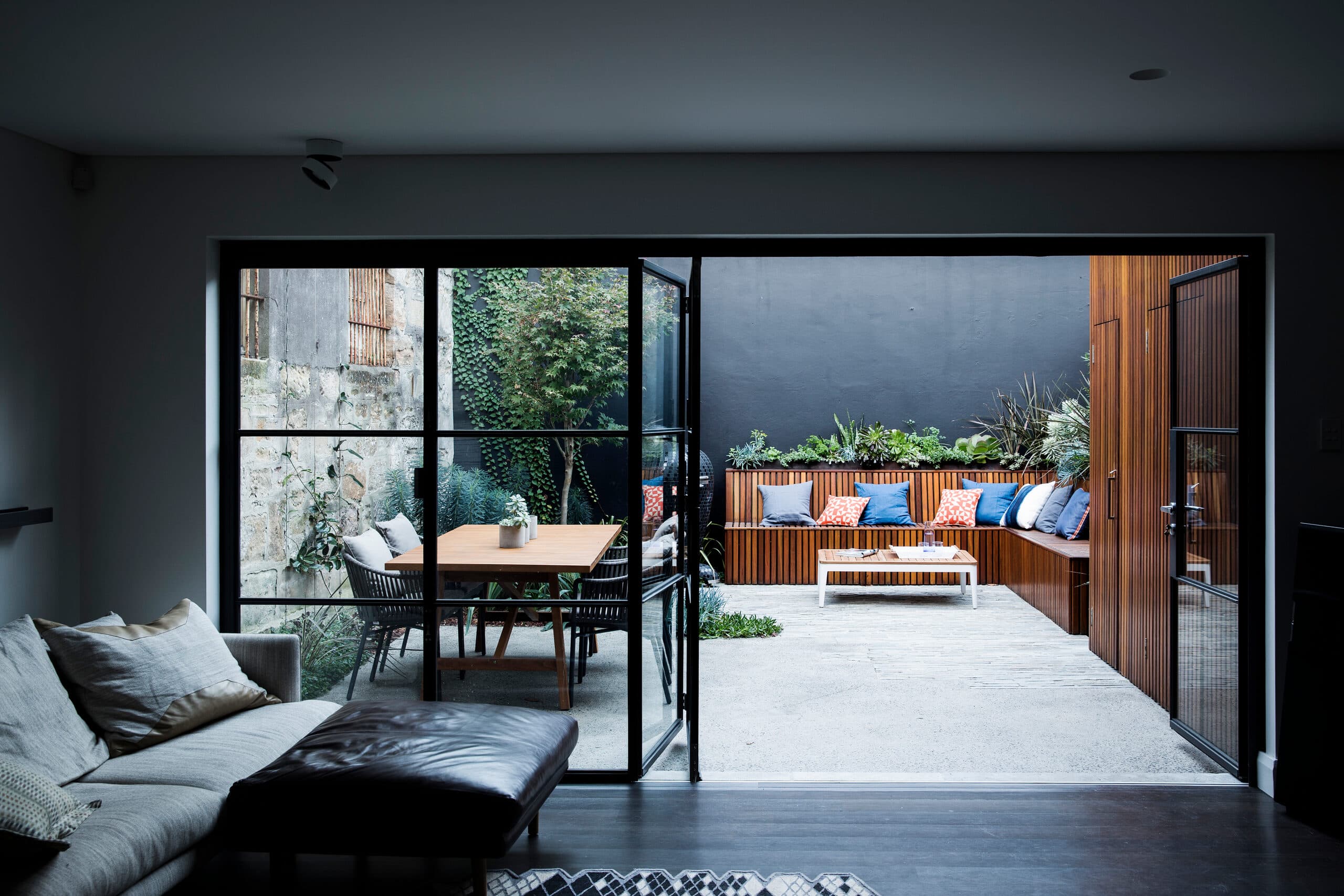 Courtyard viewed through black steel framed glass doors from the living room