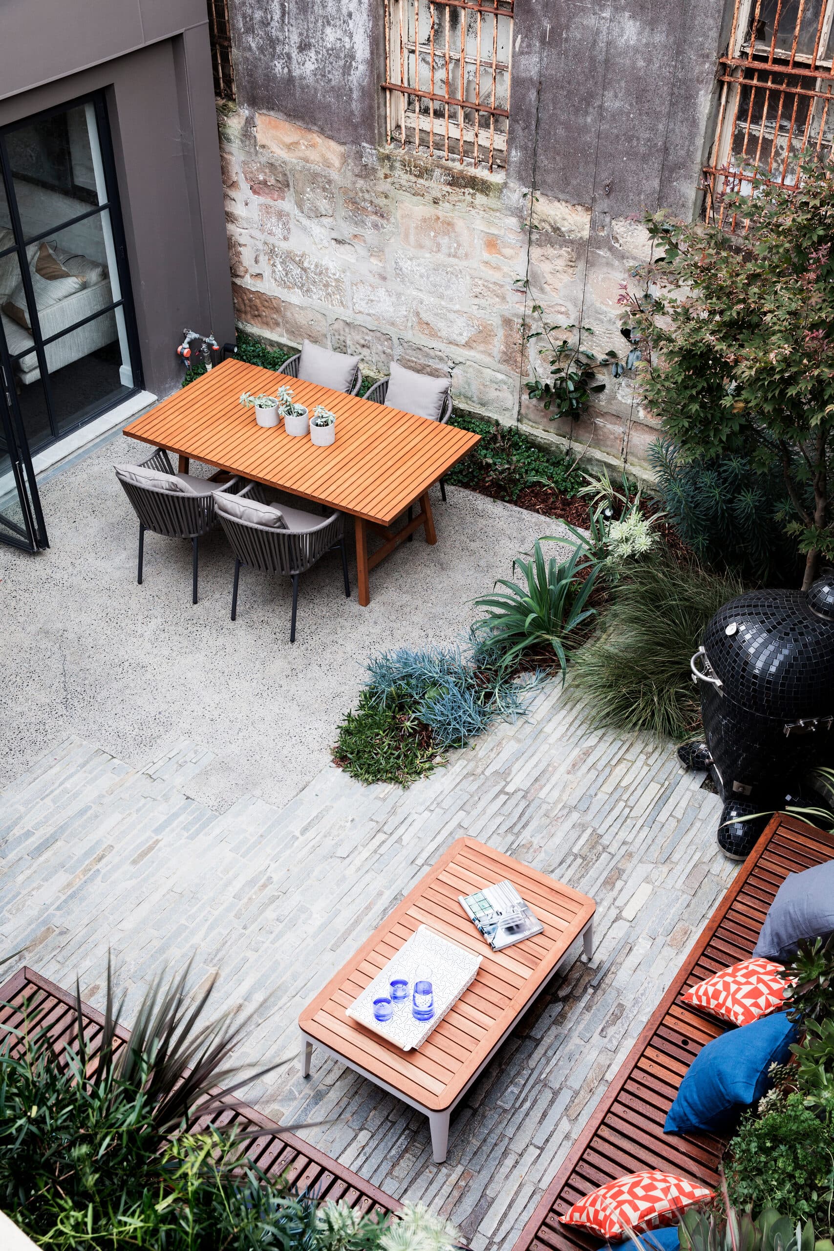 Looking down on the dining setting against a sandstone wall and split stone paving
