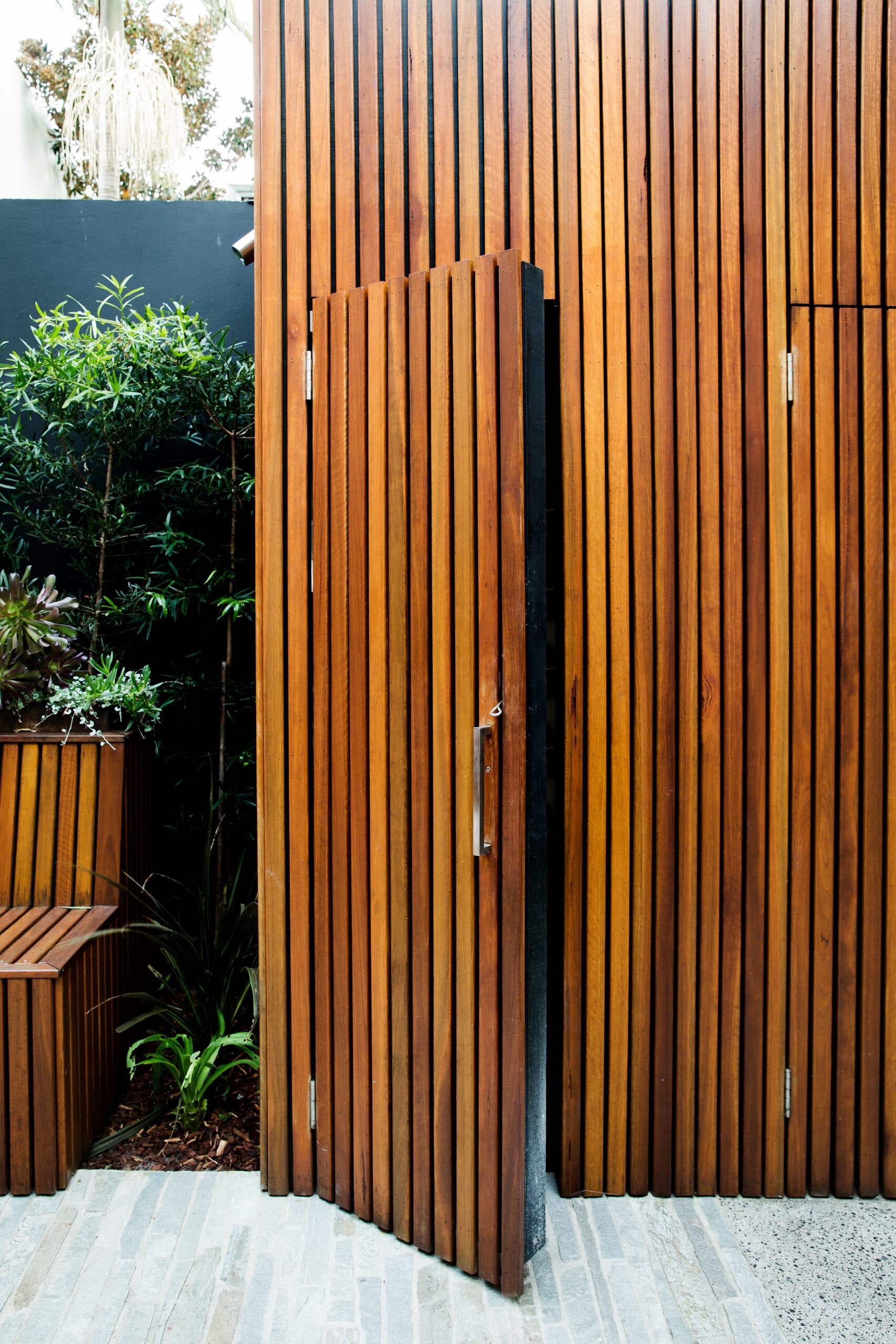 Timber battened screen wall with a concealed hinged gate and corner planter
