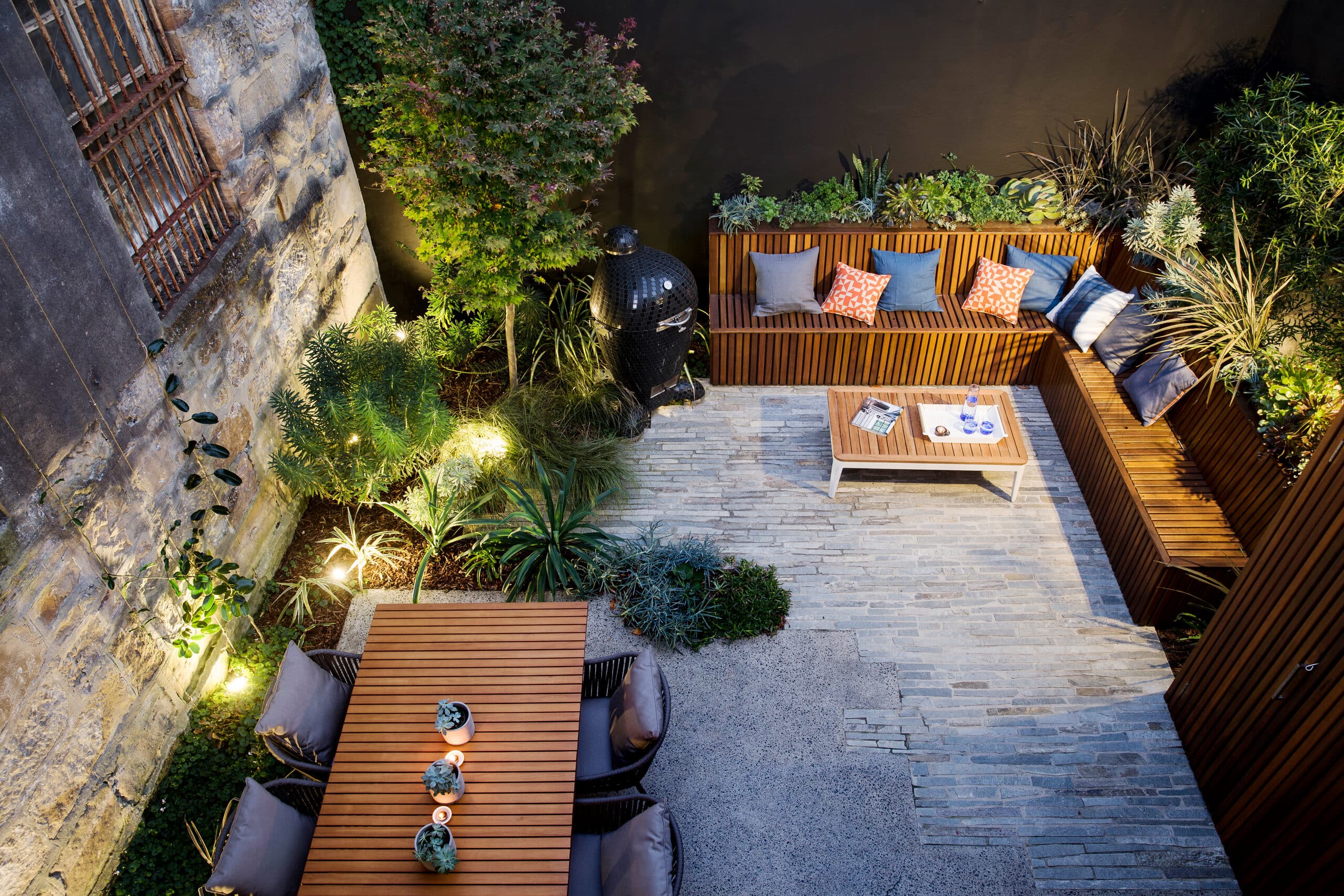 Aerial view of the lit courtyard at dusk with dining and lounge zones