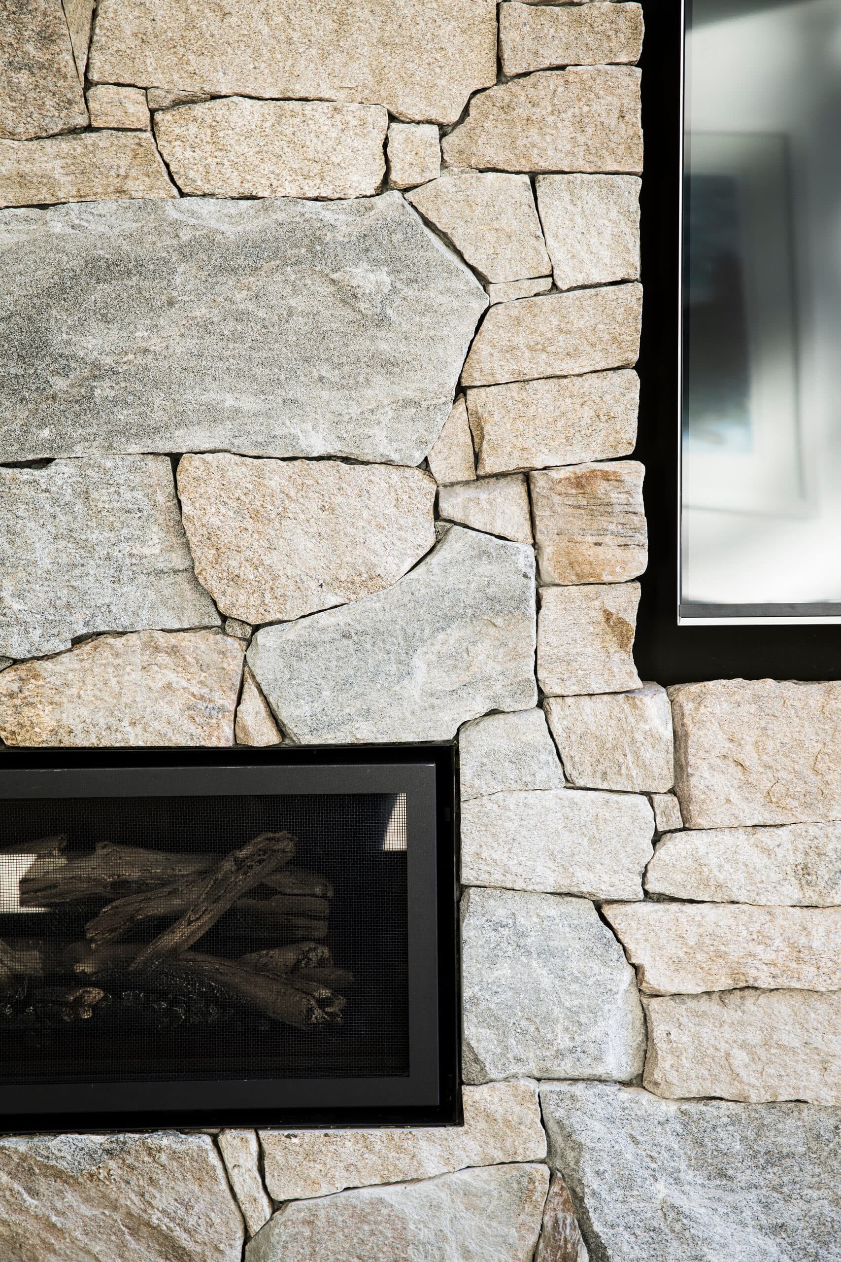 Rugged sandstone wall detail framing a gas fireplace set with driftwood-style logs