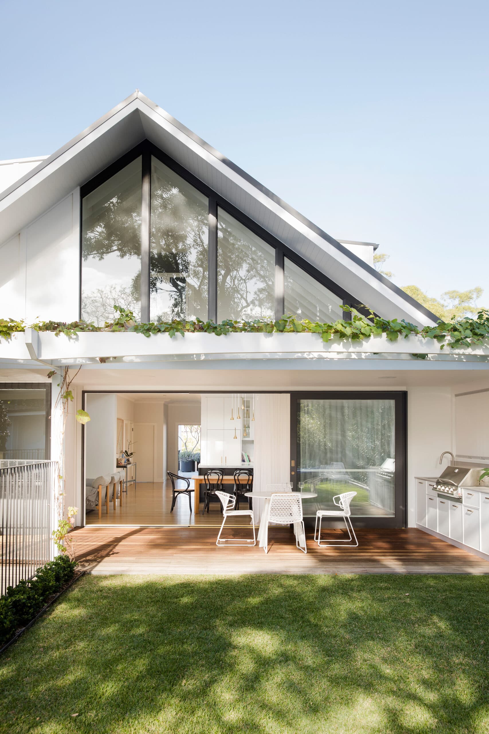 Steep glazed gable over an open living space with deck dining and built in barbecue