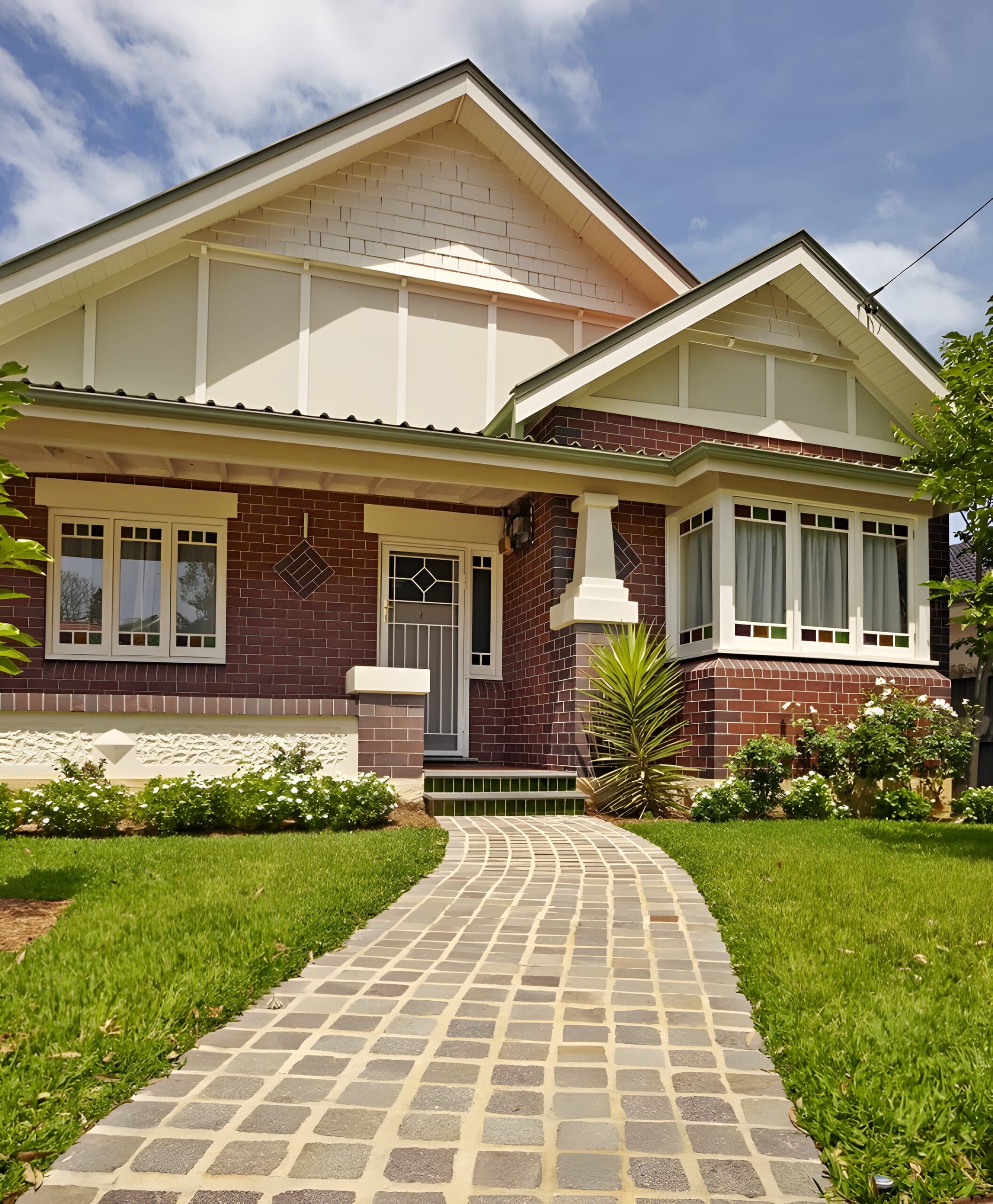 Federation brick bungalow with a bay window and a stone path edged by white flowering borders