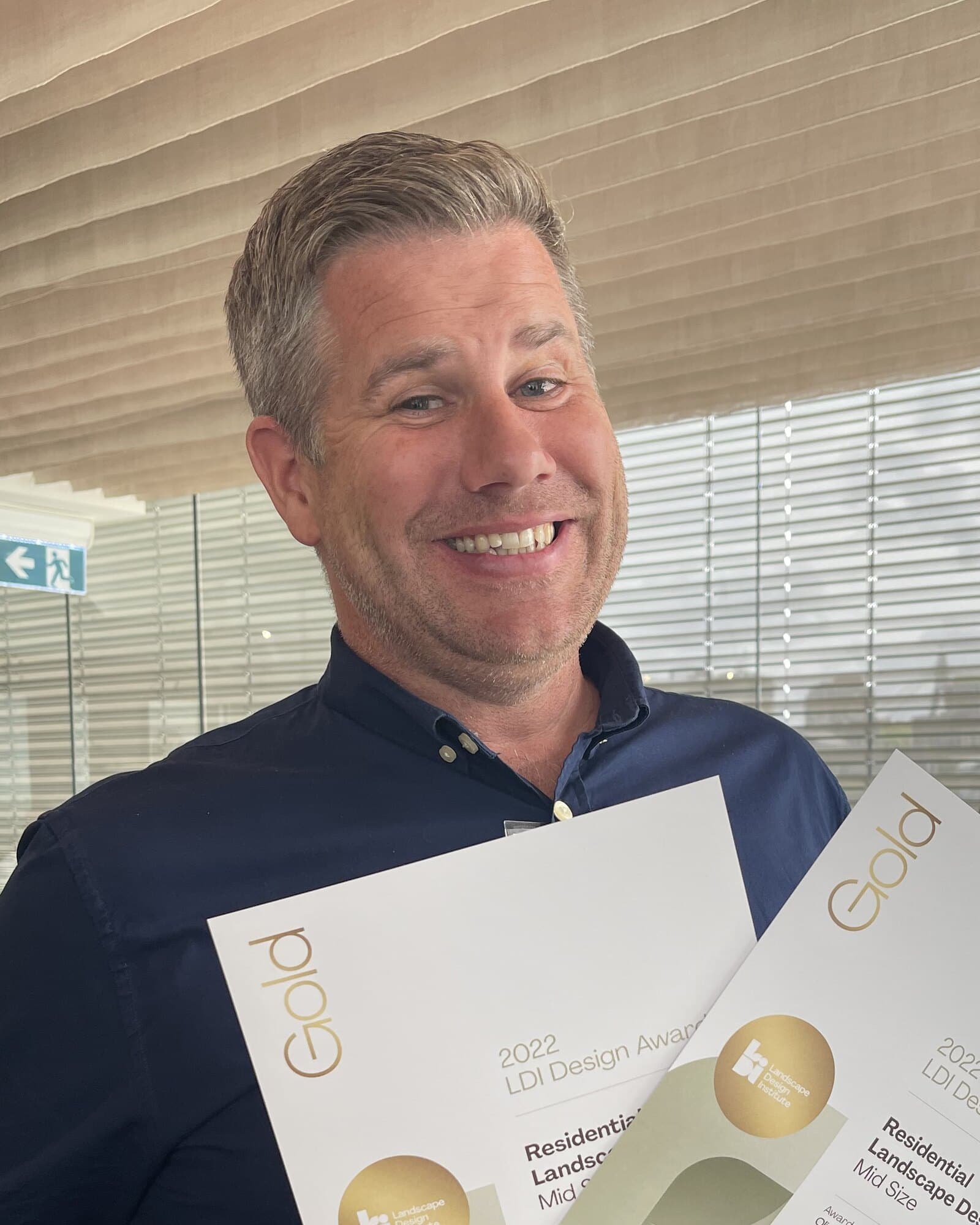 Oliver Sizeland, founder of Growing Rooms, holding two Gold LDI Design Award certificates