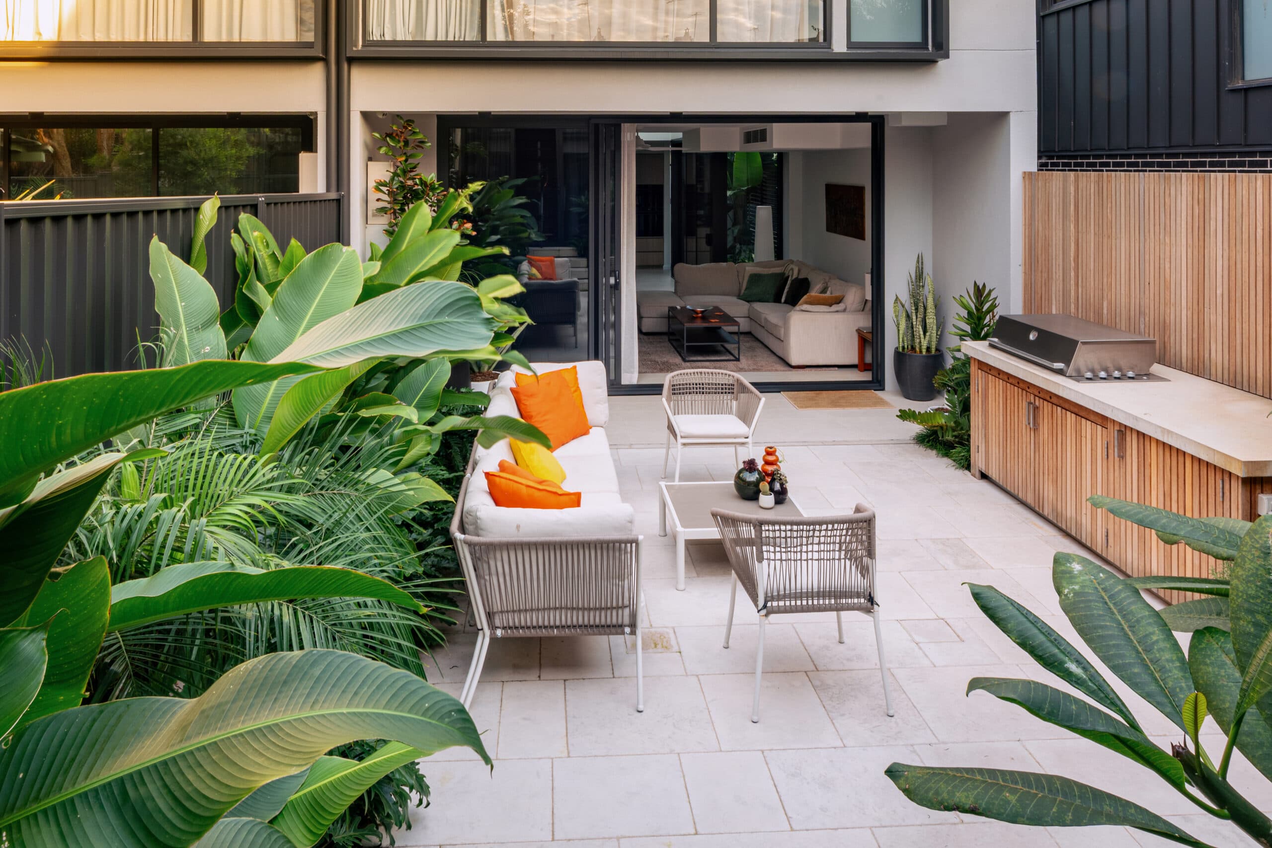 View from the home across a limestone terrace to the outdoor kitchen and layered garden.