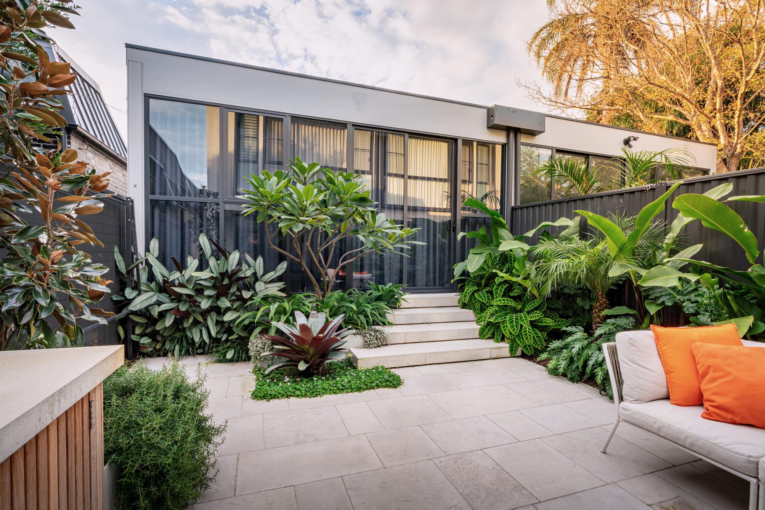 Limestone courtyard terrace leading to steps and dense subtropical planting.