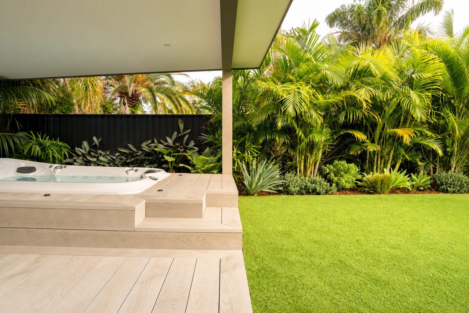 Integrated spa and pale deck framed by palms and layered tropical planting