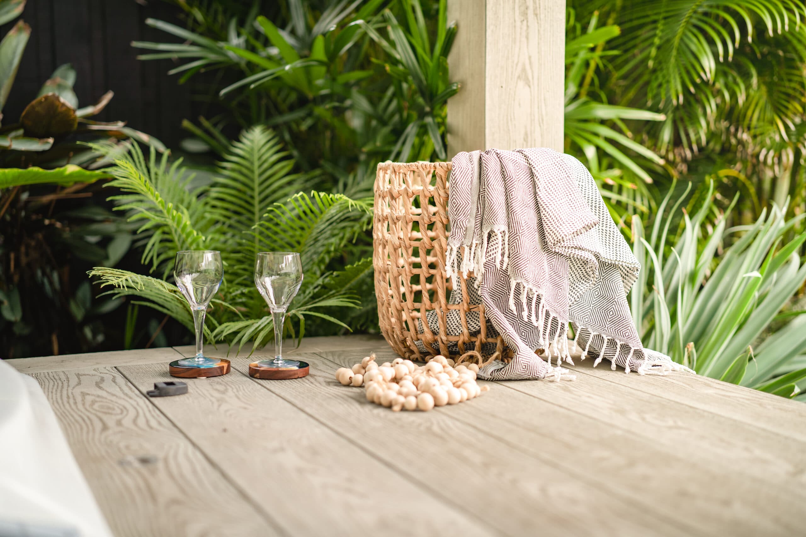 Styled timber-look deck table with lush tropical planting beyond